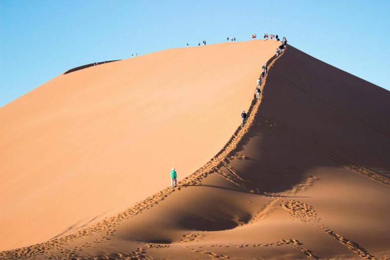Image showing people walking up a very tall sand dune.