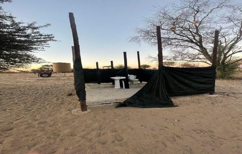 Bathroom facilities in the bush, a basin and toilet in an area closed with netting.